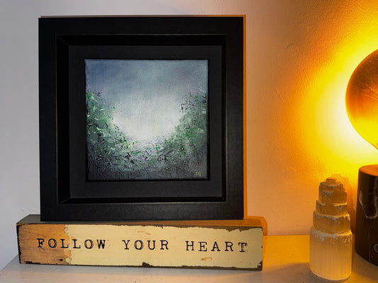Through the Green Haze abstract art by Sinéad Guilfoyle styled as shelf decor next to a warm glowing lamp and selenite crystal, demonstrating the piece's intimate scale and tactile surface.