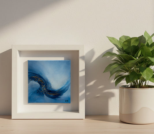 The abstract painting Emergence 2 displayed on a light oak floating shelf next to a small white pot with bright green foliage, illuminated by soft sunlight casting diagonal shadows on a white wall.