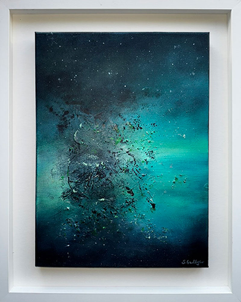 An abstract painting titled 'Cosmic Dust' by Sinead Guilfoyle. The piece is a celestial exploration of colour, featuring a dark, moody background of deep indigo and teal that transitions into a brilliant, glowing emerald green. The work is housed in a contemporary deep-set white floating frame, emphasising its depth and transformative energy.