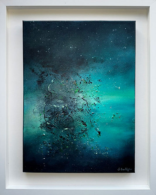 An abstract painting titled 'Cosmic Dust' by Sinead Guilfoyle. The piece is a celestial exploration of colour, featuring a dark, moody background of deep indigo and teal that transitions into a brilliant, glowing emerald green. The work is housed in a contemporary deep-set white floating frame, emphasising its depth and transformative energy.