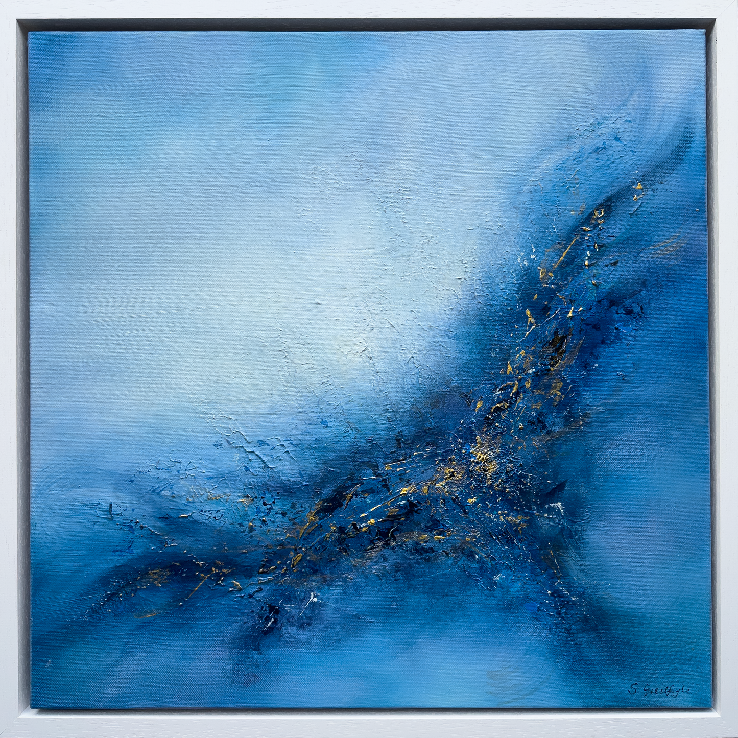Square original abstract painting titled 'Set Free' by Sinead Guilfoyle. The artwork features a vibrant exploration of blue tones, from deep navy to ethereal sky blue, with a textured, energetic central explosion of dark indigo and shimmering gold leaf accents. The composition suggests movement and transcendence, housed in a minimalist white float frame.